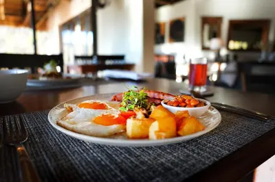 a plate of food with eggs and fruit on a table at Shibula Safari Lodge in Welgevonden Game Reserve