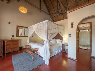 a bedroom with a canopy bed and a chair at Shibula Safari Lodge in Welgevonden Game Reserve
