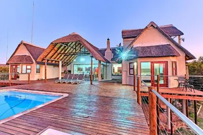 a house with a wooden deck and a swimming pool at Nyala View, Mabalingwe in Mabula