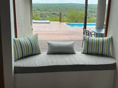 a couch with two pillows sitting on a porch at Nyala View, Mabalingwe in Mabula