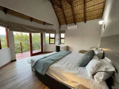 a bedroom with a large bed in a room with windows at Nyala View, Mabalingwe in Mabula