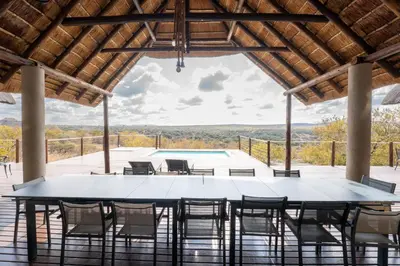 a large table and chairs on a patio with a pool at Nyala View, Mabalingwe in Mabula