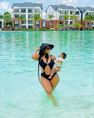 a woman in a bikini holding a baby in the water at The Blyde River Walk Estate in Pretoria