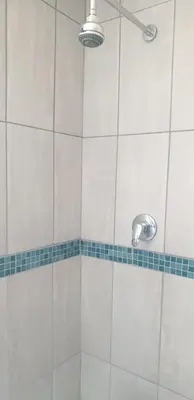 a shower with a white tiled wall and a shower head at Private Room Chez Khanyi Homestays in Pretoria