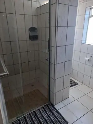 a shower with a glass door in a bathroom at Wildepeer in Nelspruit