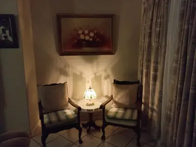 two chairs and a table with a lamp in a room at Wildepeer in Nelspruit