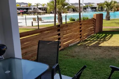 a wooden fence with a table and chairs in front of a pool at Crystal lagoon View 3Bed Apartment in Pretoria