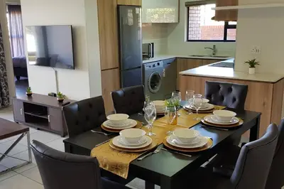 a dining room table and chairs with a table and a kitchen at Crystal lagoon View 3Bed Apartment in Pretoria