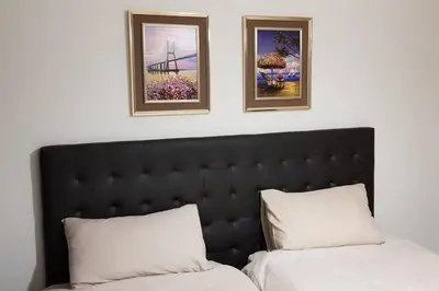 a bedroom with two beds and two pictures on the wall at Crystal lagoon View 3Bed Apartment in Pretoria