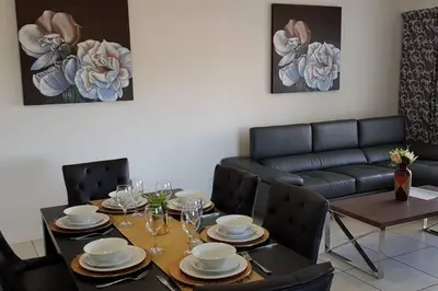 a dining room with a table and a couch at Crystal lagoon View 3Bed Apartment in Pretoria