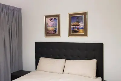 a bedroom with a bed with two pictures on the wall at Crystal lagoon View 3Bed Apartment in Pretoria