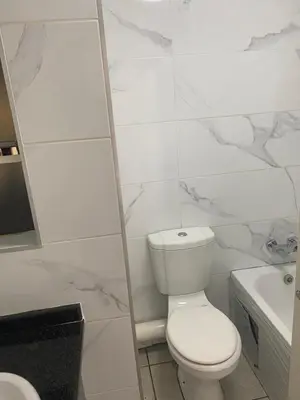 a white bathroom with a toilet and a sink at Menlyn Place in Pretoria