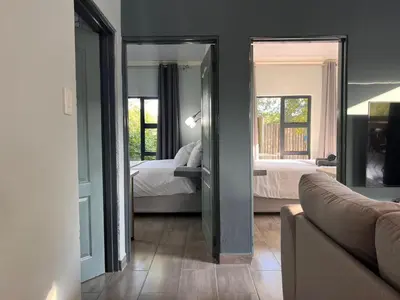 a living room with a bedroom with a bed and a mirror at Stories @ Marloth in Marloth Park