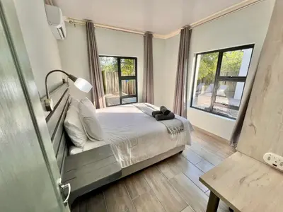 a bedroom with a bed and two windows at Stories @ Marloth in Marloth Park