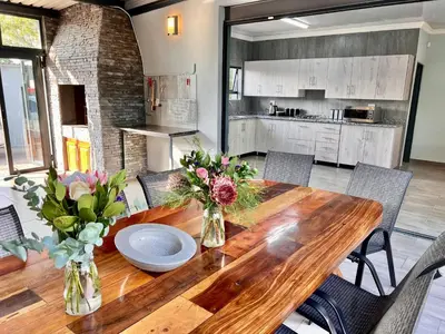 a kitchen with a wooden table with flowers in vases at Stories @ Marloth in Marloth Park