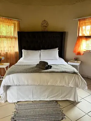 a bedroom with a large bed with a black headboard at Indlovu Inn Guesthouse in Graskop