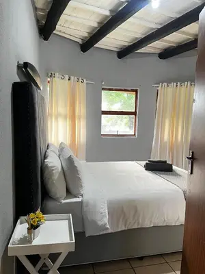 a bedroom with a white bed and a window at Indlovu Inn Guesthouse in Graskop