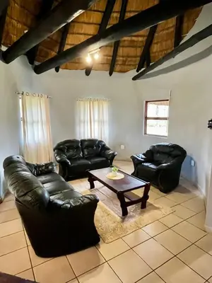 a living room with leather furniture and a coffee table at Indlovu Inn Guesthouse in Graskop