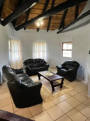 a living room with leather couches and a coffee table at Indlovu Inn Guesthouse in Graskop