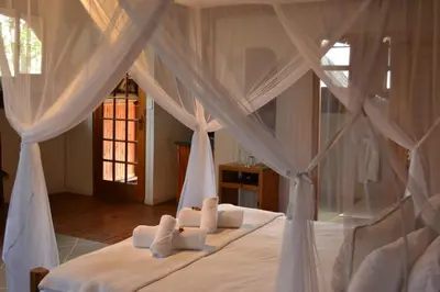 a bedroom with a bed with white sheets and pillows at Vida Nova Kruger in Marloth Park
