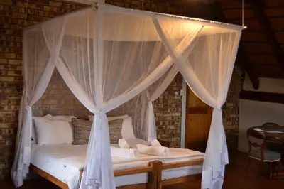 a bedroom with a canopy bed with teddy bears on it at Vida Nova Kruger in Marloth Park