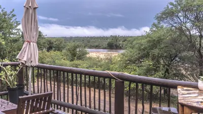 a balcony with an umbrella and a view of a river at Vida Nova Kruger in Marloth Park