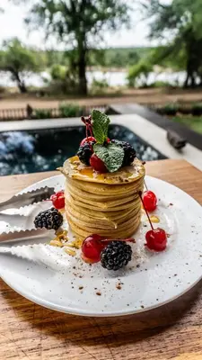 a stack of pancakes on a plate on a table at Vida Nova Kruger in Marloth Park