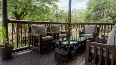 a porch with chairs and a table and a fence at Vida Nova Kruger in Marloth Park
