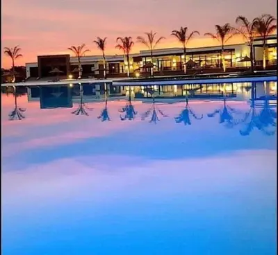 a building with a pool with palm trees in front of it at The Blyde Apartment 1287 in Pretoria