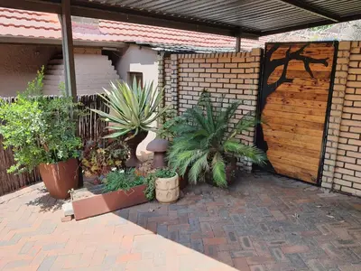 a patio with potted plants and a wooden gate at The Crooked Forest in Pretoria