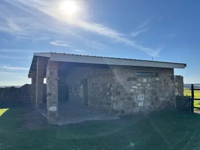a stone building in a field with the sun behind it at La Vista Farm Stay in Ermelo
