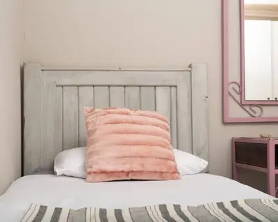 a pink pillow sitting on top of a bed at HomeSweetHome Farm Cottage in Nelspruit