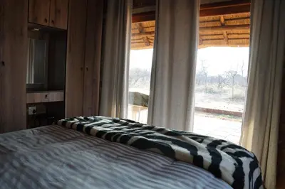 a bedroom with a bed and a large window at Kwele Game Lodge in Beauty