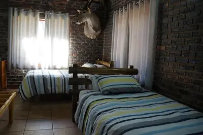a bedroom with two beds and a brick wall at Kwele Game Lodge in Beauty