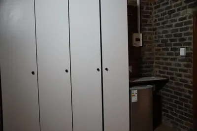 three white cabinets in a room with a brick wall at Kwele Game Lodge in Beauty
