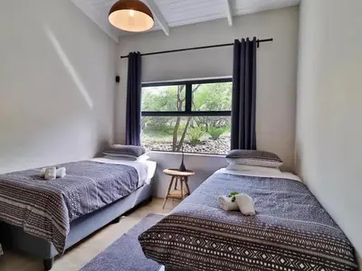 two beds in a room with a window at Chelesa by Kruger Nights in Marloth Park