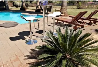 a patio with chairs and a table next to a pool at Shai's Studio in Centurion