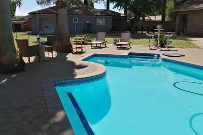 a blue swimming pool with chairs and a patio at Shai's Studio in Centurion