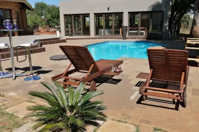two chairs and a table next to a swimming pool at Shai's Studio in Centurion