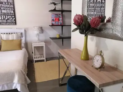a bedroom with a bed and a table with a vase of flowers at Shai's Studio in Centurion
