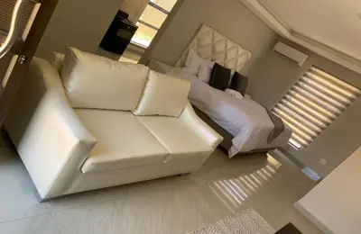 a living room with a white couch and a bed at Yami Nawe Lodge in Dennilton