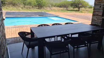 a table and chairs and a swimming pool at Musanda Villa 413 Euphoria in Naboomspruit