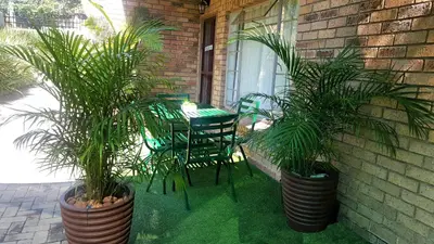 a patio with two potted plants and a table and chairs at Sunshine Self Catering in Nelspruit