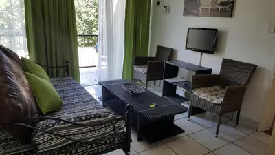 a living room with a couch and chairs and a tv at Sunshine Self Catering in Nelspruit