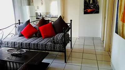 a living room with a couch with red pillows at Sunshine Self Catering in Nelspruit