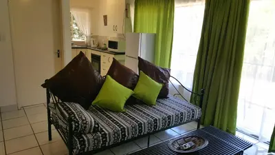 a couch with green pillows sitting in a living room at Sunshine Self Catering in Nelspruit