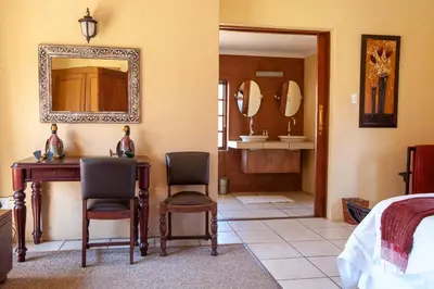 a bedroom with a bed and a desk and chairs at Crimson Cottage in Dullstroom