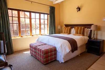a bedroom with a bed and a large window at Crimson Cottage in Dullstroom