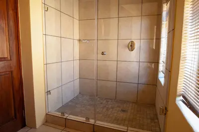 a shower with a glass door in a bathroom at Crimson Cottage in Dullstroom