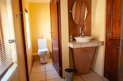 a bathroom with a toilet and a sink and a mirror at Crimson Cottage in Dullstroom